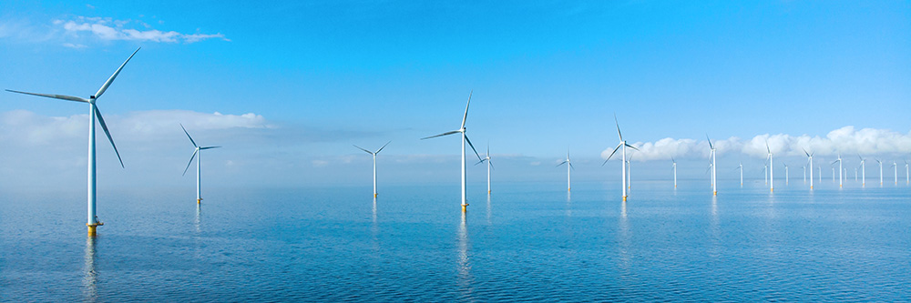 offshore wind farm with lots of wind turbines with bright blue sky and deep blue sea